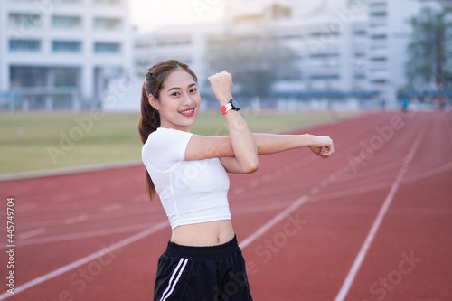 A young beautiful Asian woman in sports outfits doing stretching before workout outdoor in the park in the morning to get a healthy lifestyle. Healthy young woman warming up outdoors © EduLife Photos