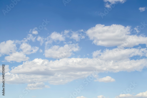 Light blue sky with layers of fluffy white clouds and darker blue toward the top - background or replacement.