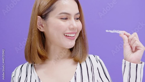 Young smiling woman holding invisalign braces in studio, dental healthcare and Orthodontic concept..