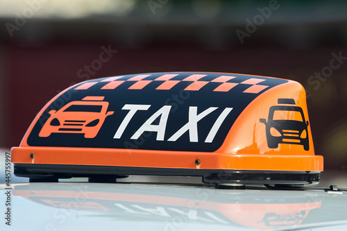 an orange taxi sign stands on the roof of the car
