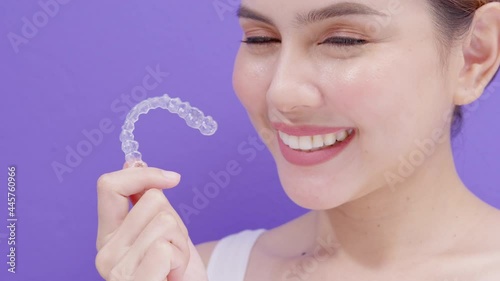 Young smiling woman holding invisalign braces in studio, dental healthcare and Orthodontic concept..