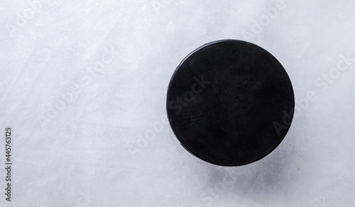 Black hockey puck on the ice rink.