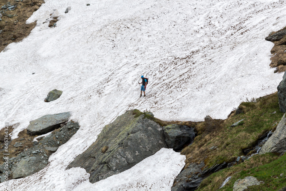 Ein Wanderer auf Schnee neben einem Gebirgsfluss im Großglockner Nationalpark, Kals Österreich