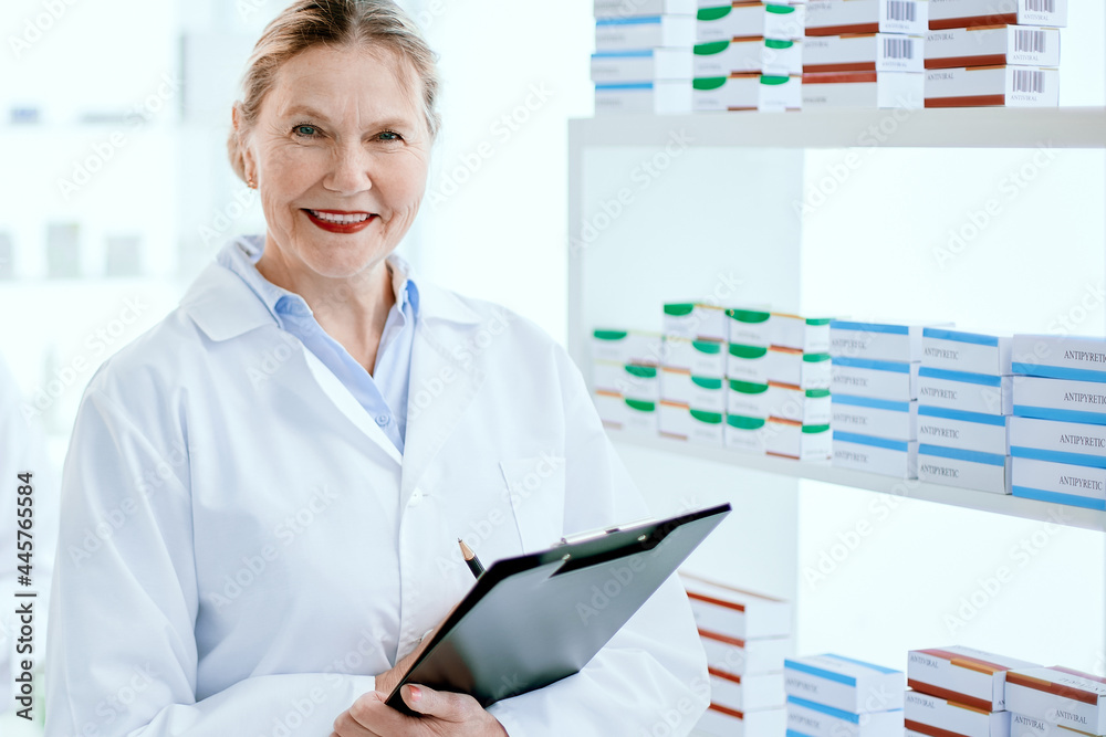 pharmacist with a clipboard and her colleague standing near a pharmacy display case . pharmacist with a clipboard and her colleague standing near a pharmacy display case .