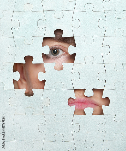 A person's face through the holes of the missing puzzles.