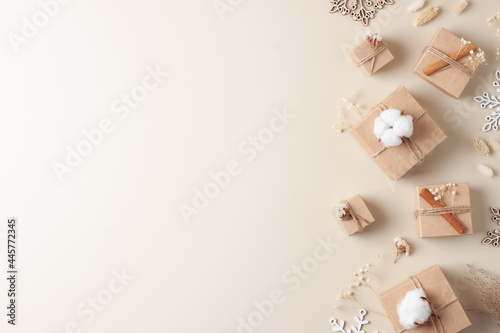 Christmas decorations with packaging gifts in craft paper and flowers on beige background. Zero waste Christmas holiday concept. Flat lay, copy space