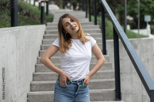 Outdoor portrait of a young woman in casual clothing on concrete stairs.