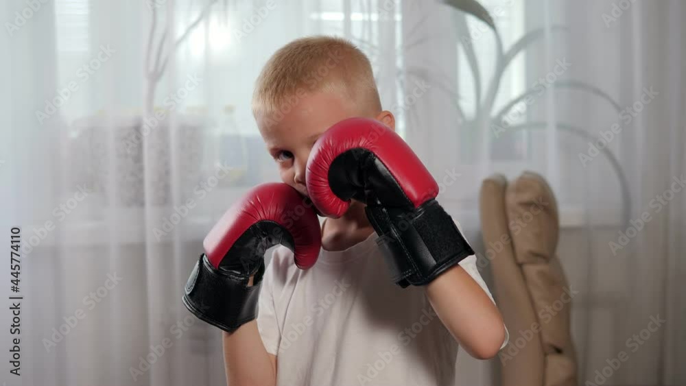 Portrait of a little boy in a red boxing gloves at home near the window. Portrait of a little boy in a red boxing gloves at home near the window.