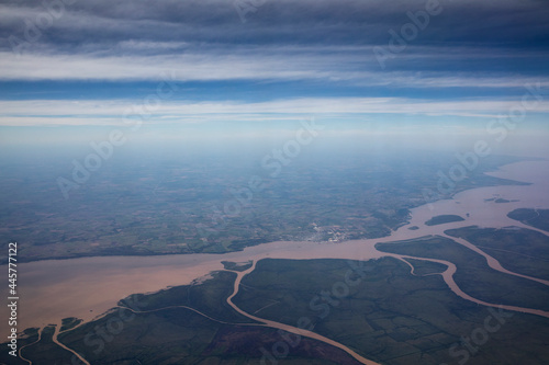 Flying. Aerial view of the Amazon river, streams and tributary channels flowing across the green tropical rainforest and field, under a beautiful blue sky. 