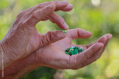 Mani umane che tengono puntine da disegno verdi su sfondo naturale. photo