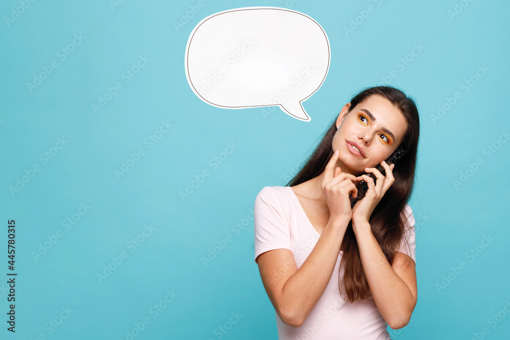 Young woman in casual clothes talking on smartphone and expresses happiness. Blue background. Young woman in casual clothes talking on smartphone and expresses happiness. Blue background.