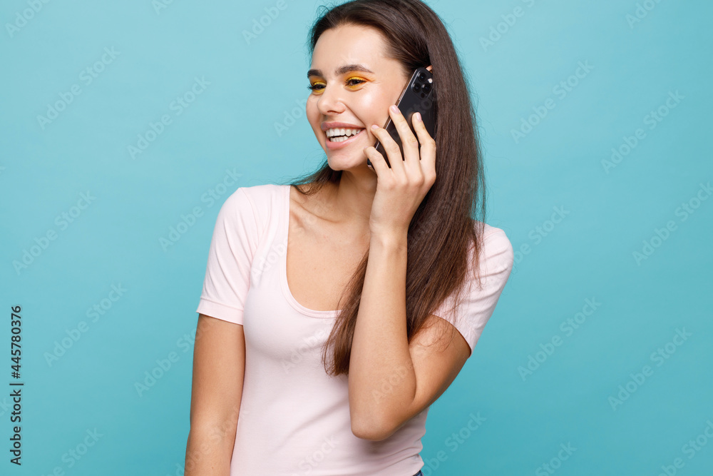 Young woman in casual clothes talking on smartphone and expresses happiness. Blue background. Young woman in casual clothes talking on smartphone and expresses happiness. Blue background.