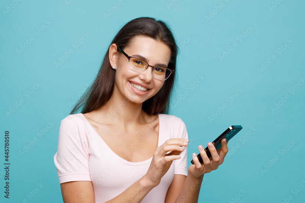 Pretty girl with smartphone in hands addicted to social media. Portrait of smiling young woman browsing on telephone. Female expresses joyful emotions. Pretty girl with smartphone in hands addicted to social media. Portrait of smiling young woman browsing on telephone. Female expresses joyful emotions.