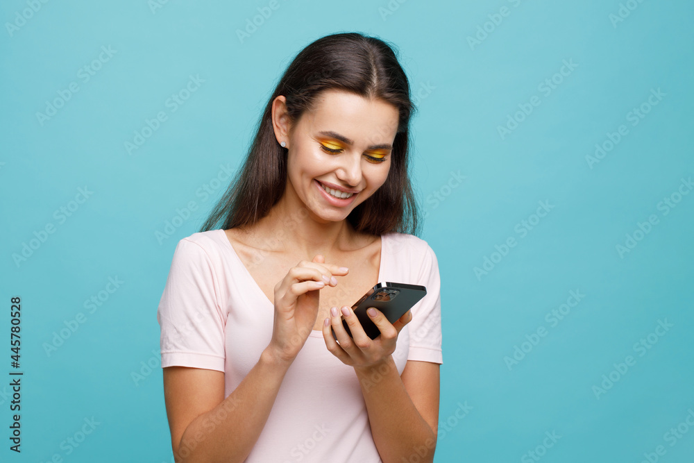 Pretty girl with smartphone in hands addicted to social media. Portrait of smiling young woman browsing on telephone. Female expresses joyful emotions. Pretty girl with smartphone in hands addicted to social media. Portrait of smiling young woman browsing on telephone. Female expresses joyful emotions.