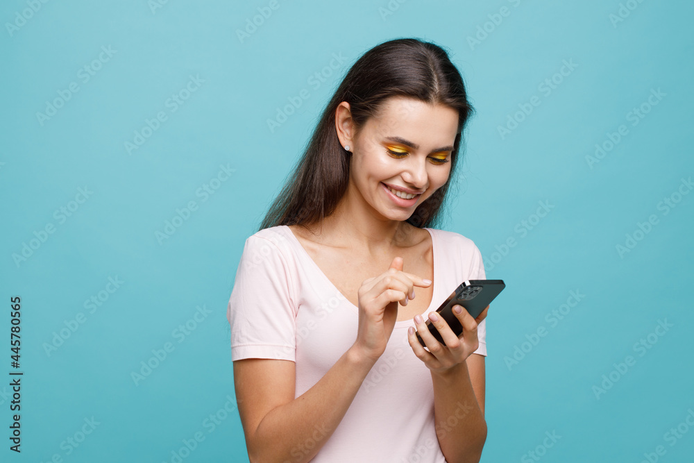 Pretty girl with smartphone in hands addicted to social media. Portrait of smiling young woman browsing on telephone. Female expresses joyful emotions. Pretty girl with smartphone in hands addicted to social media. Portrait of smiling young woman browsing on telephone. Female expresses joyful emotions.