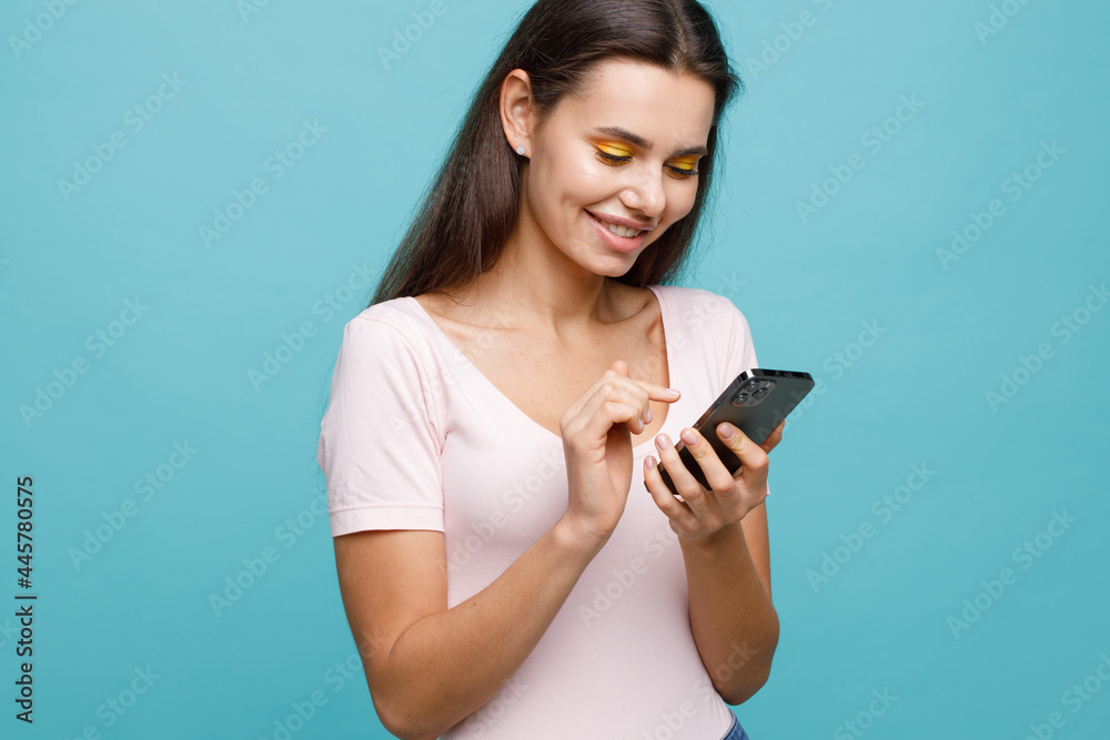 Pretty girl with smartphone in hands addicted to social media. Portrait of smiling young woman browsing on telephone. Female expresses joyful emotions. Pretty girl with smartphone in hands addicted to social media. Portrait of smiling young woman browsing on telephone. Female expresses joyful emotions.