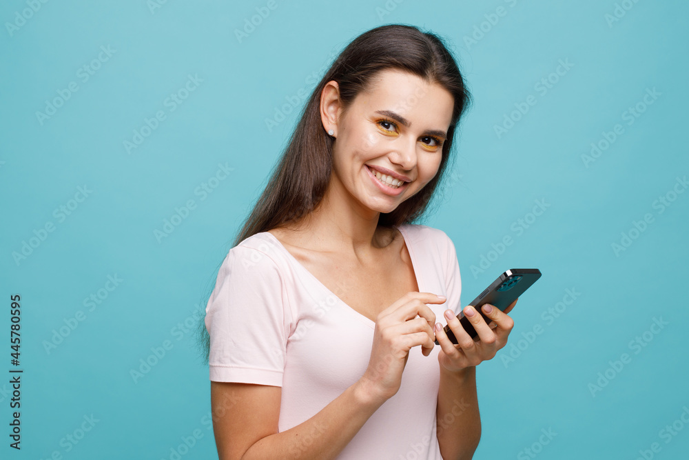 Pretty girl with smartphone in hands addicted to social media. Portrait of smiling young woman browsing on telephone. Female expresses joyful emotions. Pretty girl with smartphone in hands addicted to social media. Portrait of smiling young woman browsing on telephone. Female expresses joyful emotions.