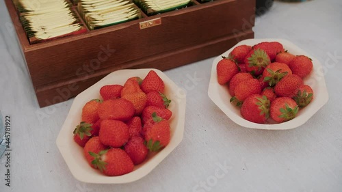Catering buffet.. Close-up of a tea table with wooden sticks, tea bags in a wooden box, strawberries on a white plate. 