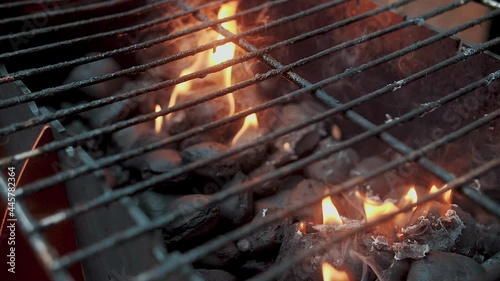 Close up. Empty hot barbecue grill with a flame of fire and smoke is burning, black round coal. Super slow motion.