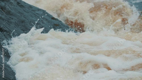 Strong flow of water with splashes and foam in slow motion. Powerful raging river flow. Extreme steep river threshold. Emergency water discharge. Dam break, spring flood, dangerous weather conditions.