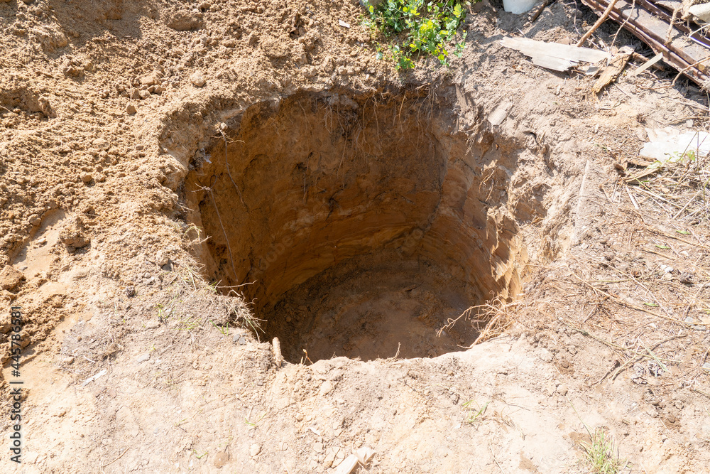 a deep hole is dug in the ground, a sinkhole in the ground - obrazy, fototapety, plakaty 