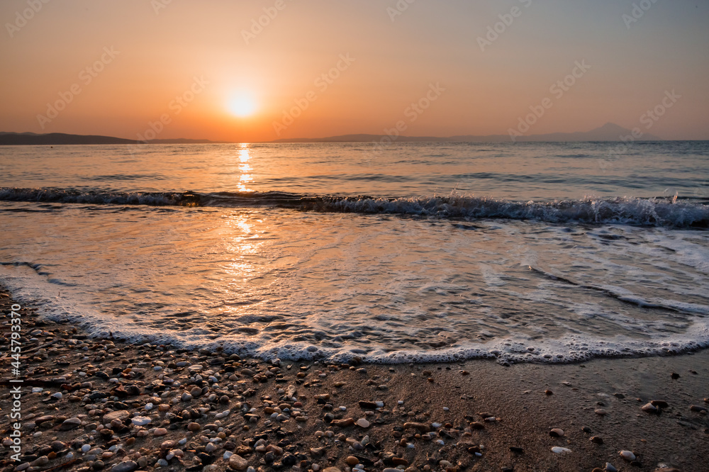 sunset on the beach with waves with Mount Athos silhouette on the horizon sunset on the beach with waves with Mount Athos silhouette on the horizon