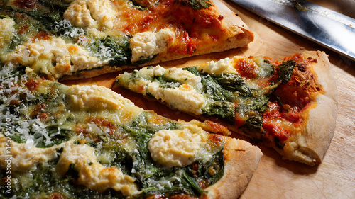 Italian pizza with spinach, mozzarella and parmesan. Thin crispy pizza base. Close-up.