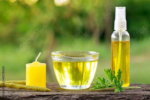 Citronella (Scent Geranium). Pelagorium Citrosum essence oil in a cup with a candel incence and spray bottle. Over a wood plank with green blurre3de background and copy space.