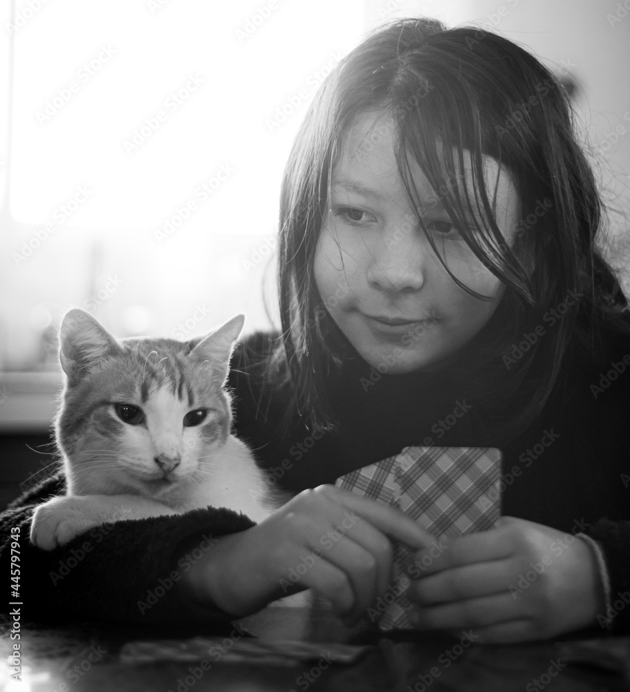 Niña jugando naipes con su gato naranja Stock Photo | Adobe Stock