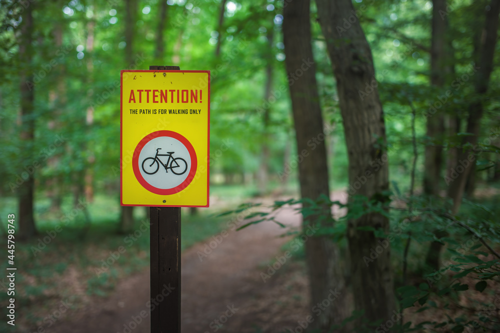 Sign prohibiting bicycles in front of the hiking trail in the forest.