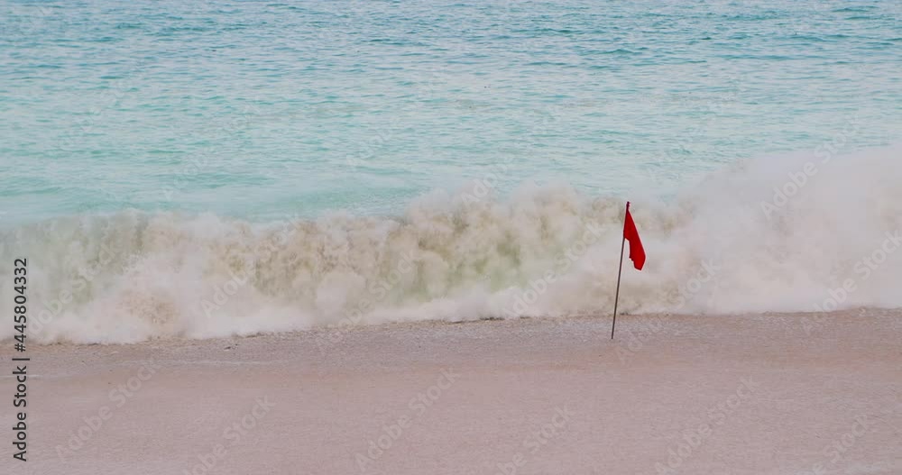 Red flag alert. Beach is danger for swimming. Red flag fluttering to alert people not to swim because of strong storm wind and waves. Sunny beach during warm afternoon with huge blue waves. Lifeguard. Red flag alert. Beach is danger for swimming. Red flag fluttering to alert people not to swim because of strong storm wind and waves. Sunny beach during warm afternoon with huge blue waves. Lifeguard.