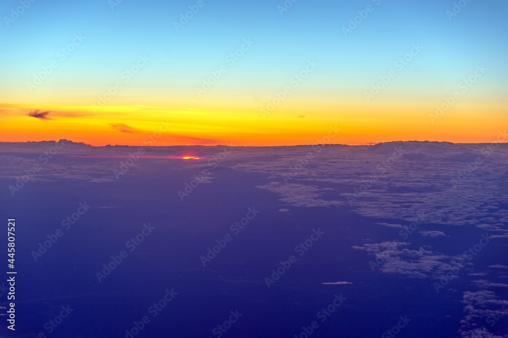 View from the plane at sunrise. Flying above the clouds