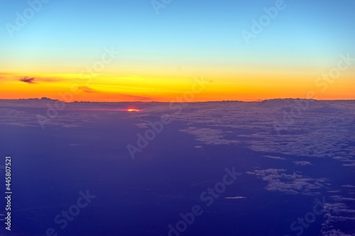 View from the plane at sunrise. Flying above the clouds