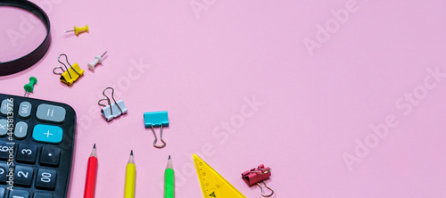Various office supplies on a pink background. Back to school concept. Calculator and magnifier with pencils of different colors, top view © Екатерина Переславце