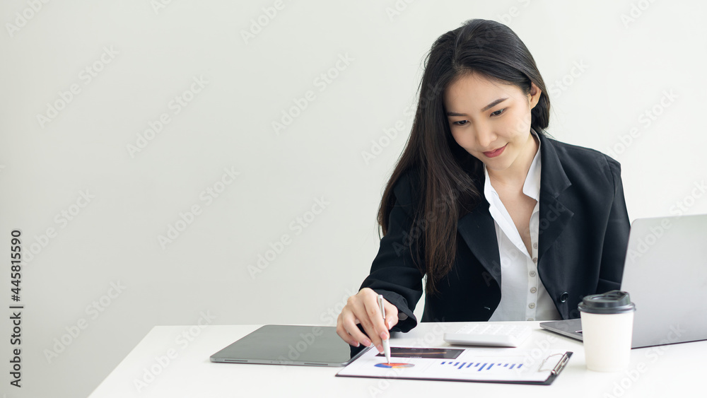 Businesswoman working with laptop and graphing documents to analyze and calculate company finances.