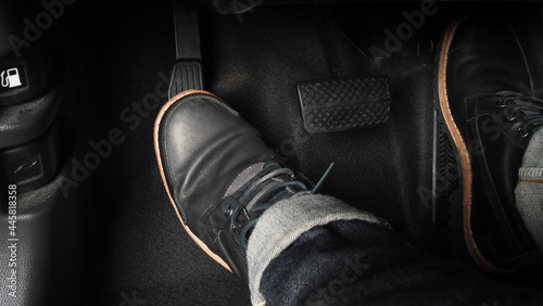 Man foot and accelerator and brake pedal inside the car or vehicle and copy space which black color leather shoe stepped on it for speed up or control automobile pace power. Automobile Driving concept