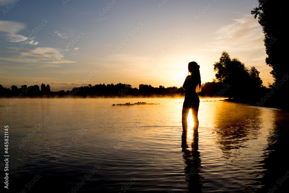 Junge Frau im Sonnenaufgang am Flußufer