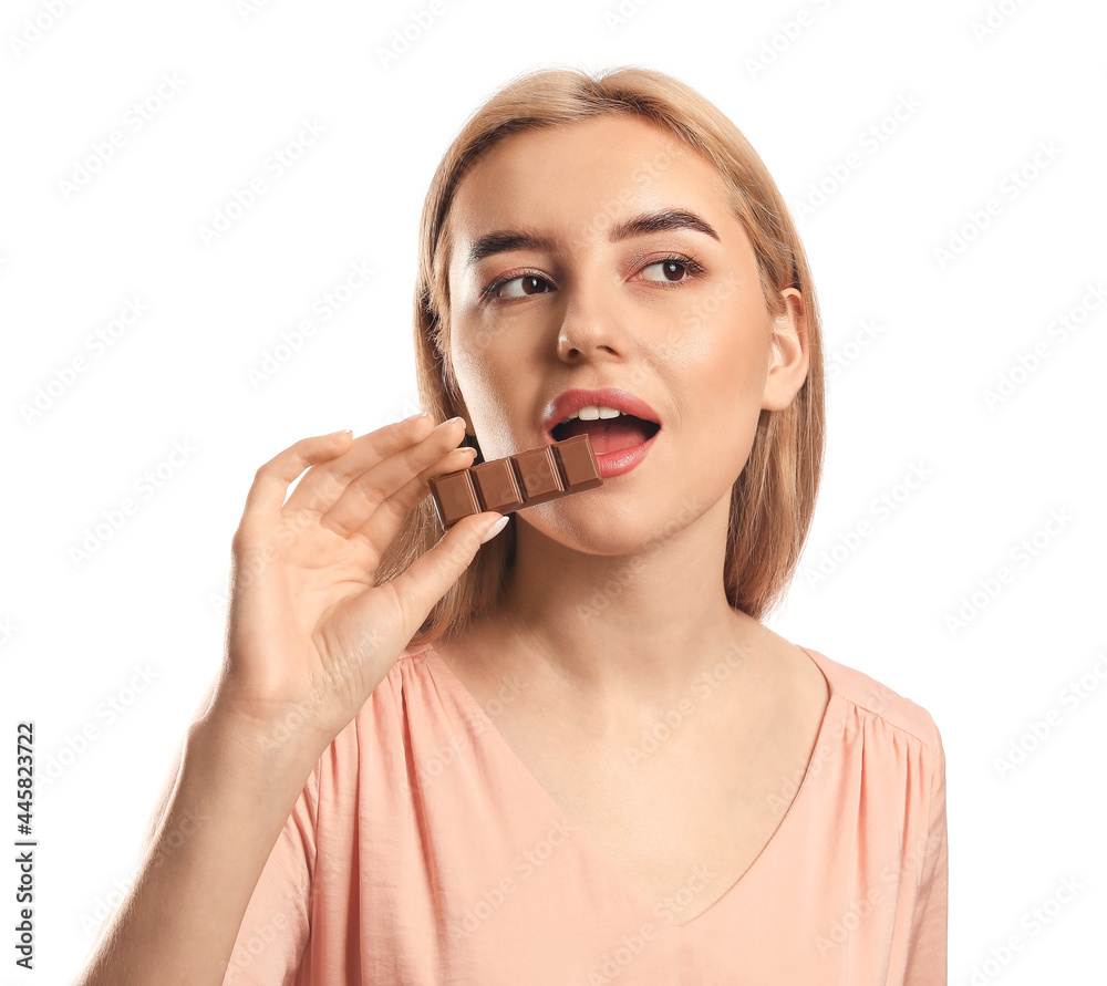Beautiful young woman eating tasty chocolate on white background Beautiful young woman eating tasty chocolate on white background