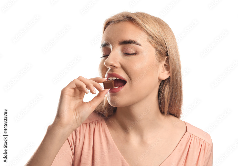 Beautiful young woman eating tasty chocolate on white background Beautiful young woman eating tasty chocolate on white background