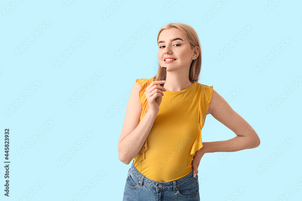 Beautiful young woman with tasty chocolate on color background Beautiful young woman with tasty chocolate on color background