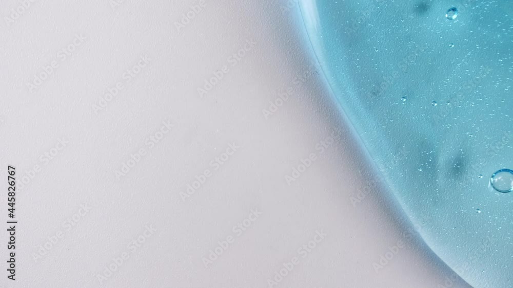 Blue Transparent Cosmetic Gel Cream With Molecule Bubbles Flowing On The Plain White Surface. Macro Shot. High quality 4k footage