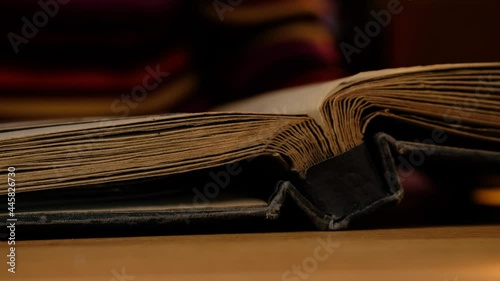Elderly woman looks through an family album with old photos at table at home.