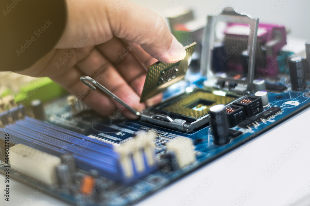 A young man is using his hand to pick up a PC computer CPU on a motherboard with many zips to upgrade a new CPU. A young man is using his hand to pick up a PC computer CPU on a motherboard with many zips to upgrade a new CPU.