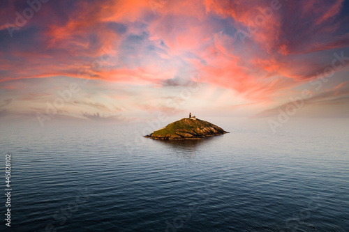 The Ballycotton lighthouse isolated in the middle of the sea at sunset