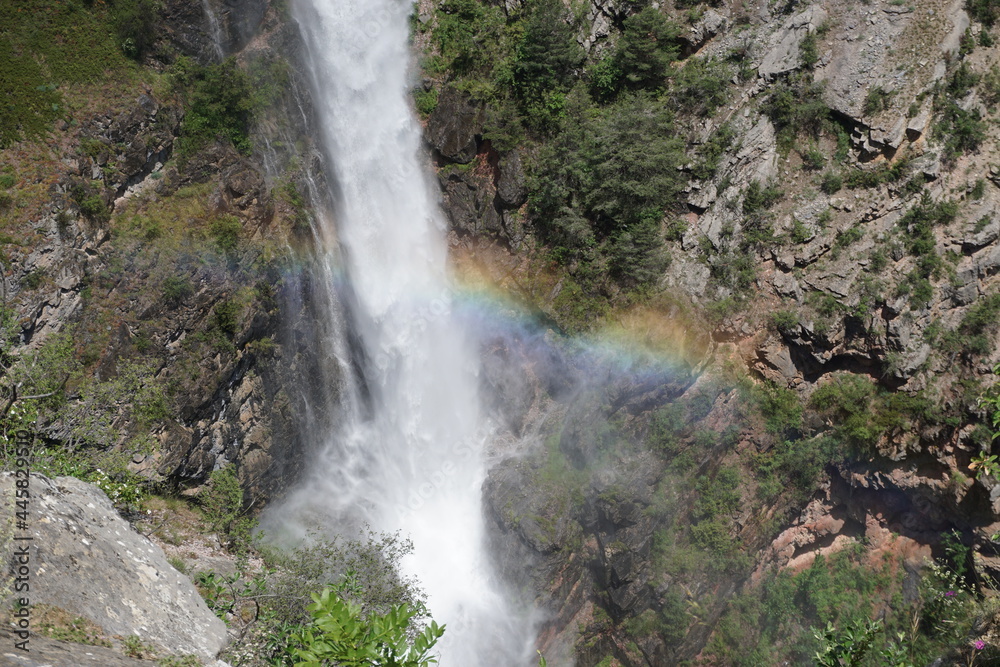 waterfall in the mountains of the alps, france with a rainbow across waterfall in the mountains of the alps, france with a rainbow across