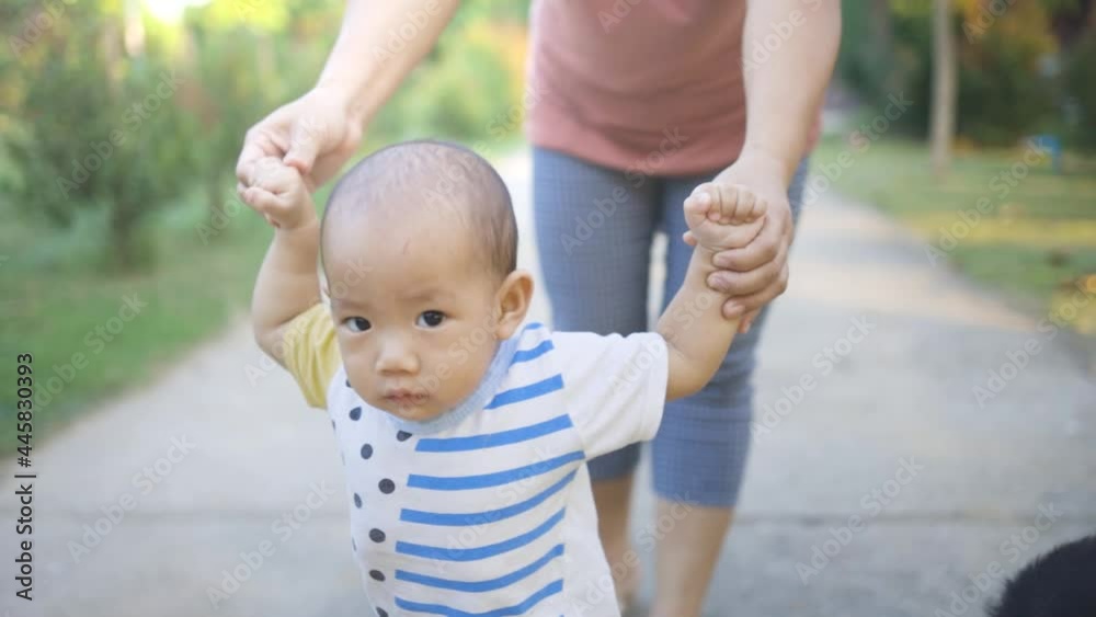 Baby boy practicing to walk, mother helping Baby boy practicing to walk, mother helping