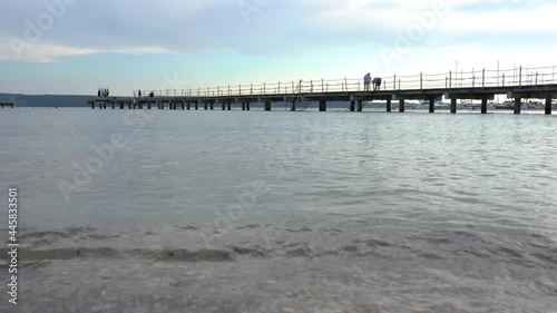 Wallpaper Mural Low angle view of people walking on long walkway pier in Portoroz, Slovenia. Leisure on dock in summer evening. Calm Adriatic Sea. Real time, wide angle, handheld Torontodigital.ca