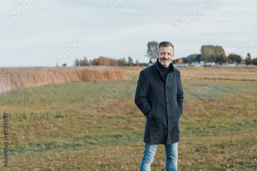 Trendy middle-aged man standing in a rural field