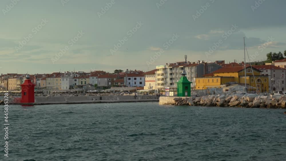 View of small historic seaside town Piran, Slovenia. Beautiful summer evening. Waves hitting rocky shore. Famous landmark at Adriatic Sea. Handheld, real time, wide angle View of small historic seaside town Piran, Slovenia. Beautiful summer evening. Waves hitting rocky shore. Famous landmark at Adriatic Sea. Handheld, real time, wide angle