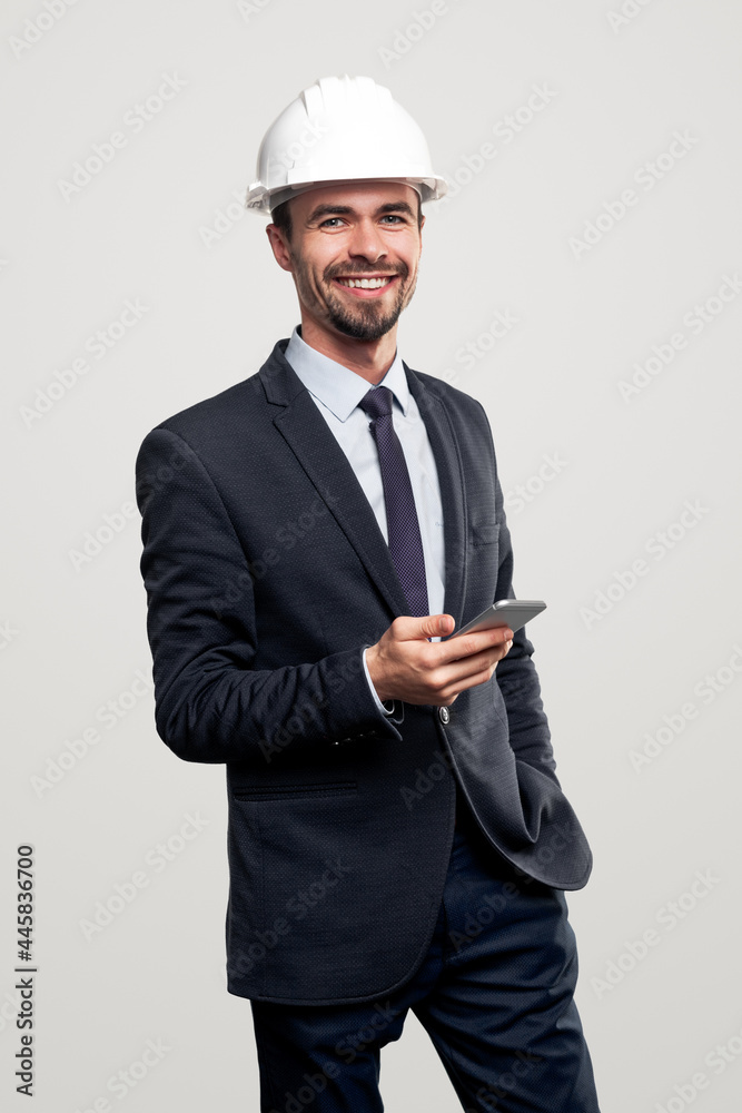 Smiling engineer in hardhat using smartphone Smiling engineer in hardhat using smartphone